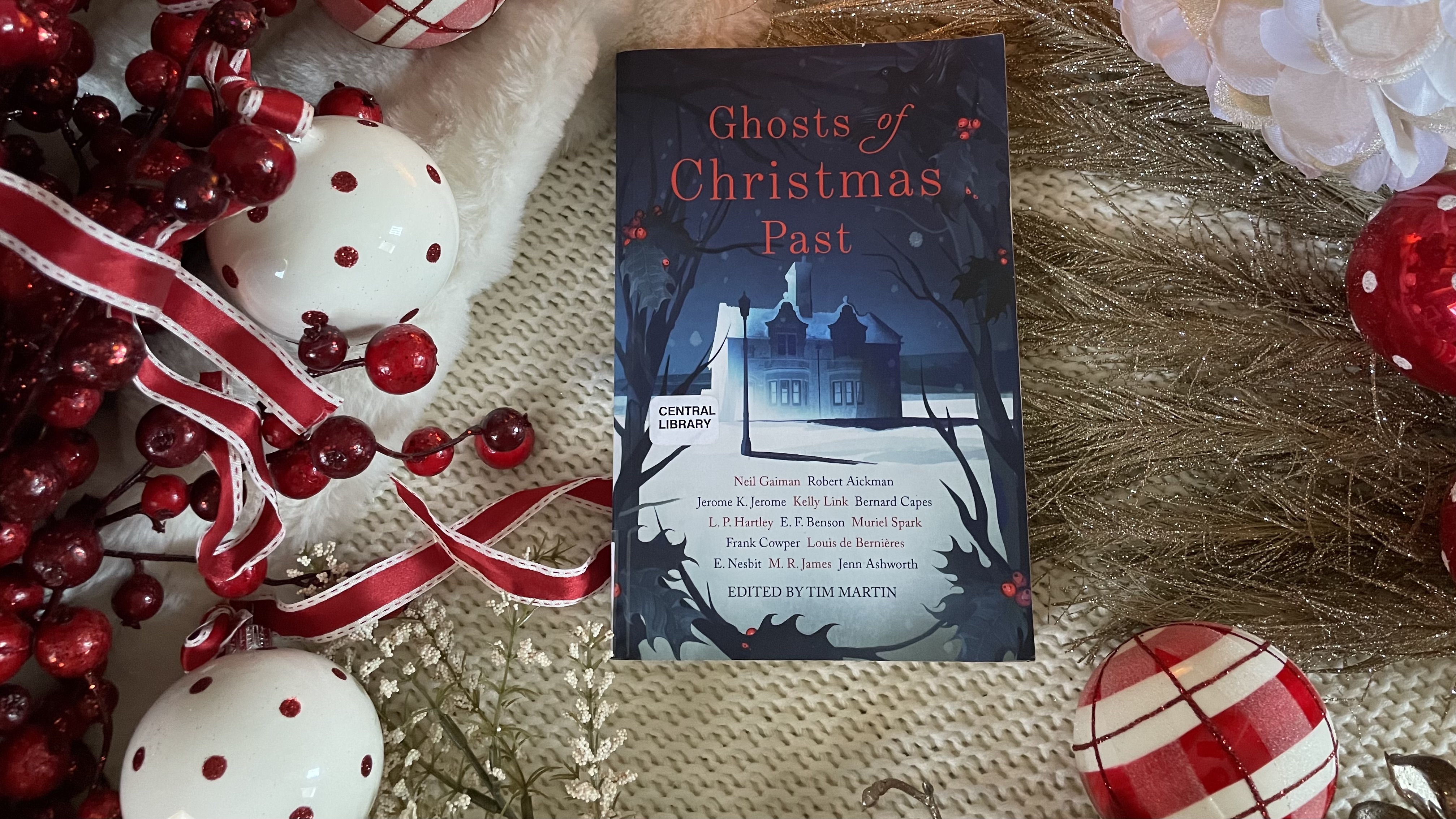 Christmas ghost story book Ghosts of Christmas Past, surrounded by holiday ornaments and berries in red and white